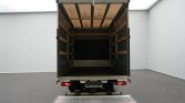 Open cargo truck with empty interior and loading ramp lowered, ready for loading in a clean, white-walled space.
