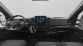 Interior of a modern vehicle showing a central touchscreen, steering wheel with controls, and climate dials with driver and passenger seats visible.