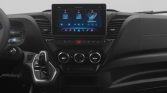 Center console car interior with a large touchscreen infotainment display and climate control dials below it, gear lever to the left