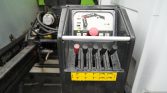 Industrial machine control panel with five black levers and one red lever, yellow safety diagram beneath, and a wet enclosure edge.