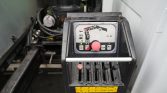 Close-up of an industrial control panel with six vertical levers (one red) and a red emergency-like knob, on a wet black housing with a yellow warning label at the bottom.