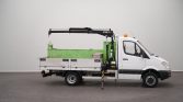 White utility truck with a hydraulic crane on the flatbed, stabilizing legs deployed in a studio setting