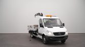 White Mercedes tow truck with a crane on a flatbed, orange beacon lights, parked indoors.