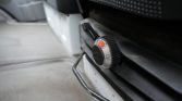Close-up of a round metal control knob with a black grip and orange indicator in a car interior, set to a mid-range number.
