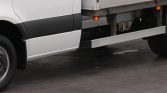 White semi-truck side view showing the long underside step and attached trailer undercarriage.
