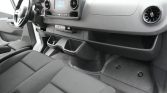 Driver's-side view of a modern car interior: steering wheel, center infotainment screen, round air vents, and front storage pockets on the dashboard.
