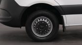 Close-up of a van's front wheel: black hubcap with silver rim and visible tire tread.