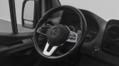 Mercedes‑Benz van interior showing steering wheel with controls, dashboard gauges, and a side mirror visible through the window