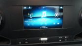 Car dashboard touchscreen showing Radio, Media via Bluetooth, and Vehicle Info icons in a blue display area.