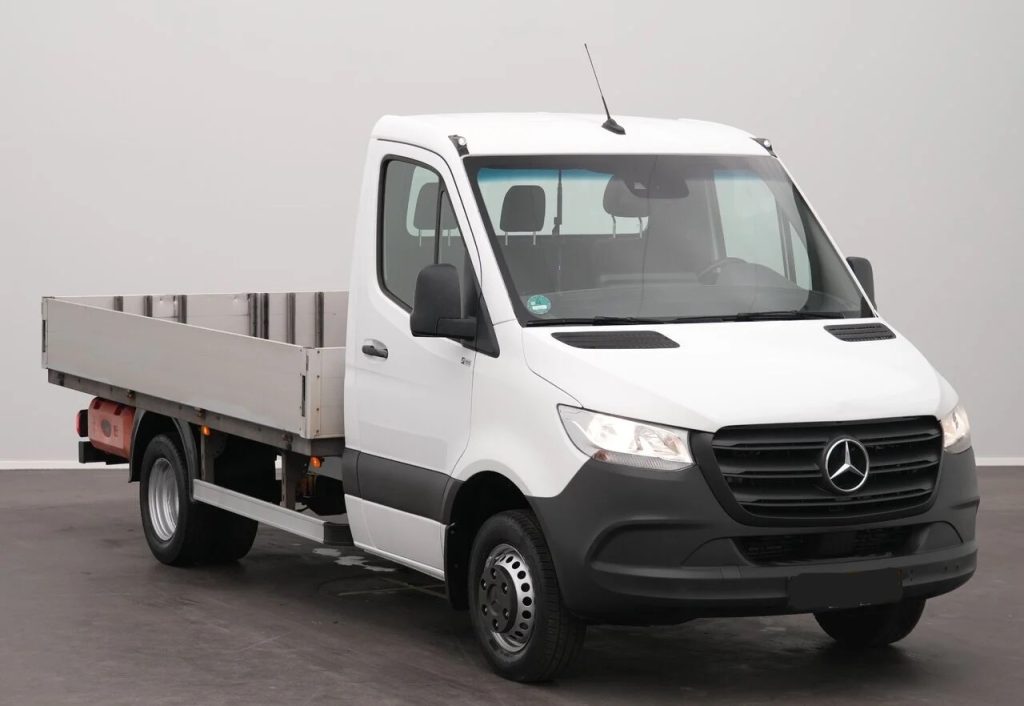 White Mercedes-Benz flatbed truck in a studio setting, angled to show front and cargo bed.