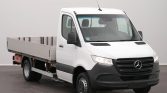 White Mercedes-Benz flatbed truck in a studio setting, angled to show front and cargo bed.