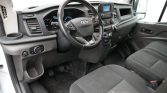 Interior of a vehicle showing the steering wheel, instrument cluster, center console, and front seats they are in a dark gray cabin