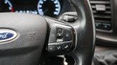 Close-up of a Ford steering wheel with built-in control cluster on the right, including OK button, arrows, and media/phone buttons.