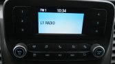 Car stereo display showing FM1 at 10:34 with 'L1 RADIO' on the screen and surrounding control buttons on both sides.