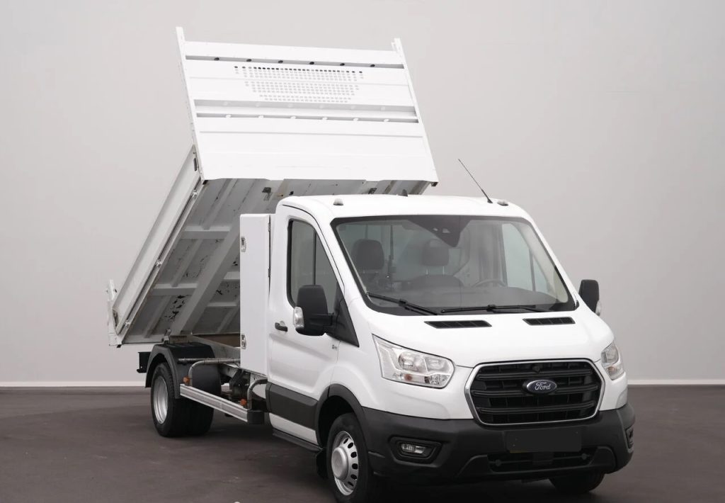 White Ford dump truck with its bed raised, ready to unload material.