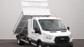White Ford dump truck with its bed raised, ready to unload material.