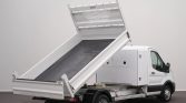 White utility truck with a raised tilt-bed for unloading cargo, in a neutral studio setting.