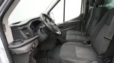 Interior of a van cockpit with steering wheel, dashboard, and two front seats visible from the passenger side door.