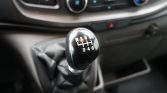 Manual gear shift knob in a car showing the 6-speed pattern (R, 1-3, 2-4-6) with surrounding center console visible behind it.
