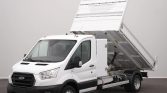 White Ford dump truck with its bed raised for unloading, indoors or in a studio setting