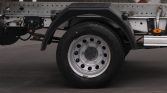 Rear truck wheel with steel rim and black fender over a flatbed chassis.