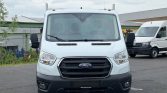 White Ford transit-style van viewed head-on in a parking lot; prominent grille and front bumper with Ford emblem.