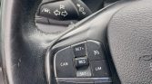 Close-up of a car steering wheel with cruise control buttons labeled CAN, RES, SET+, SET-, and LIM; stalk behind shows turn signals and lights.