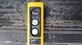Yellow handheld measurement device with two round gauges and a small display, resting on a dirty truck bed surface.