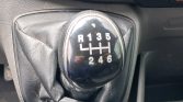 Close-up of a car's manual gear shift knob showing gear pattern R 1 3 5 / 2 4 6 (reverse to the left).