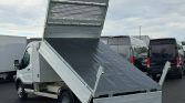 White utility truck with a raised tilt bed ready to unload, in a parking lot
