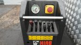 Close-up of a HIAB control panel with five levers, a pressure gauge, and a red emergency stop on a rugged black housing.