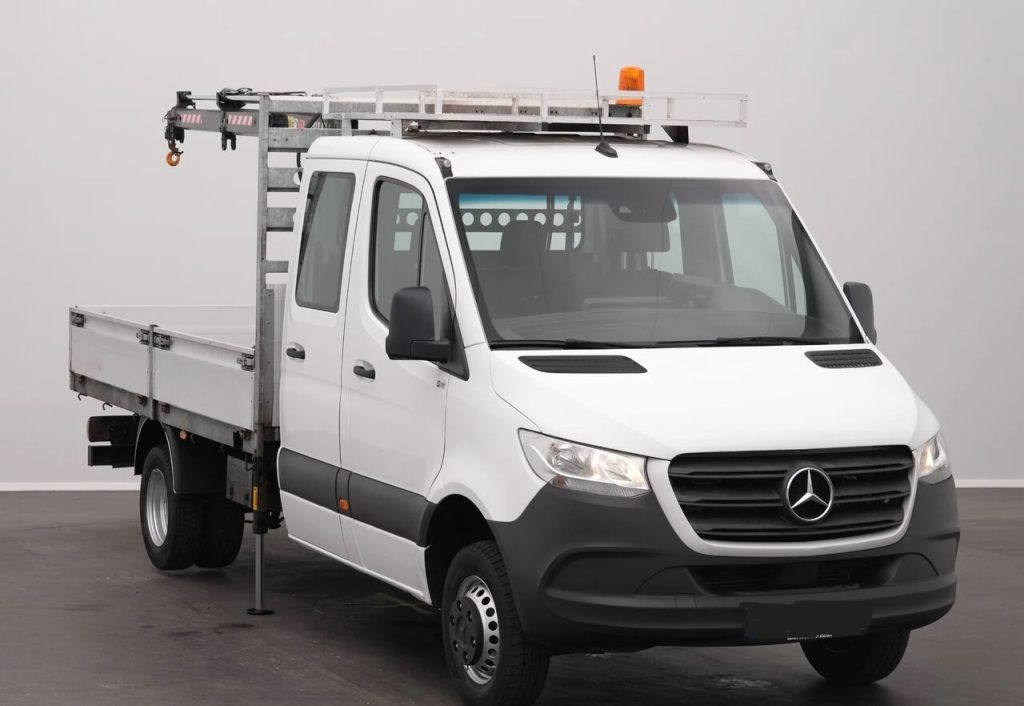 White Mercedes-Benz utility truck with a metal ladder rack on top and an orange beacon, indoors in a studio setting.