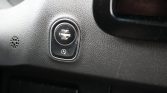 Close-up of a car's push-button ignition labeled Start Engine Stop with an Auto Start-Stop symbol below on a textured dashboard.