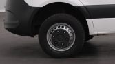 Front wheel and fender of a white van, showing a steel rim and tire on a dark surface.