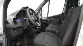Driver's cabin of a white van with black seats, steering wheel, and dashboard gauges visible. (Informative)