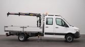 White utility truck with a crane mounted on the flatbed and the stabilizing leg deployed.