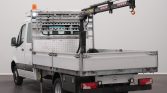 White utility truck with a hydraulic crane on the flatbed and orange beacon light on top, parked indoors.