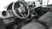 Interior of a Mercedes van cockpit with steering wheel, dashboard, and front seats visible