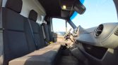 Interior of a van showing a long back bench seat and the driver’s cockpit with steering wheel and dashboard visible