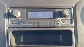 Car stereo control panel with display showing 08:25 and labeled buttons: RADIO, MEDIA, TEL, SETUP, and navigation controls; empty storage tray below.