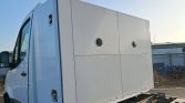 Side view of a white delivery truck with a tall, boxy cargo area photographed outdoors.