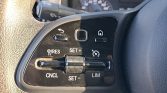 Steering wheel control panel featuring cruise control buttons (RES, SET+, SET-, CNCL, LIM), a textured roller, and a small home/menu button on a glossy black plate.