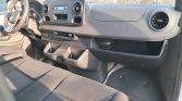 Front interior of a van: dashboard with circular vents, radio, and storage shelves under the dash