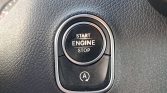 Close-up of a car's engine start/stop push button on a textured dashboard, with an 'A' circular arrow symbol below.
