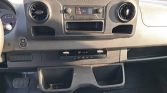 Dashboard of a Sprinter van showing the central radio, two round air vents, climate controls, and open storage pockets in the lower dash.