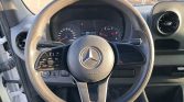 Mercedes-Benz steering wheel with control buttons, inside a car cockpit and instrument cluster in the background