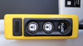 Yellow handheld control panel with two round dial buttons showing left and right arrows; 'SPX' label on the right.