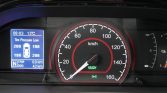 Car dashboard with a large speedometer (0–160 km/h) and a blue info display showing tire pressure warnings and trip data, ready indicator lit in green, date/time on left panel, fuel gauge on right edge.