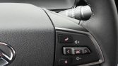 Close-up of right-side steering wheel controls: phone answer, volume, SRC, arrows, and mute on a black panel.