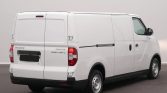 White panel cargo van photographed from the rear-left, showing double rear doors, a side cargo panel, black bumper, and steel wheels.